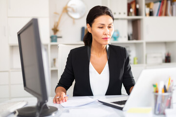 Smiling woman working with papers and laptop in office