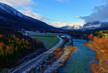 Mountain valley in autumn colors with a highway running along a turquoise glacial river.