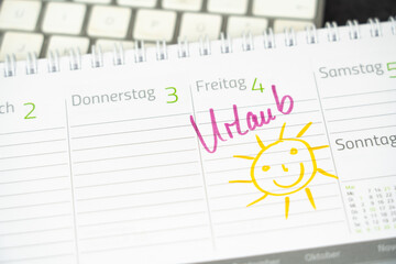 The entry of the German word for vacation and the drawing of a smiling sun in a desk calendar - 391186111