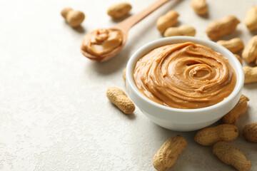 Spoon and bowl with peanut butter, and peanut on white background
