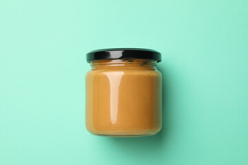 Blank jar with peanut butter on mint background