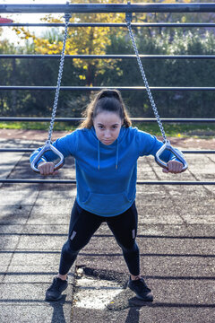 junge frau macht krafttraining im park in blauem pullover