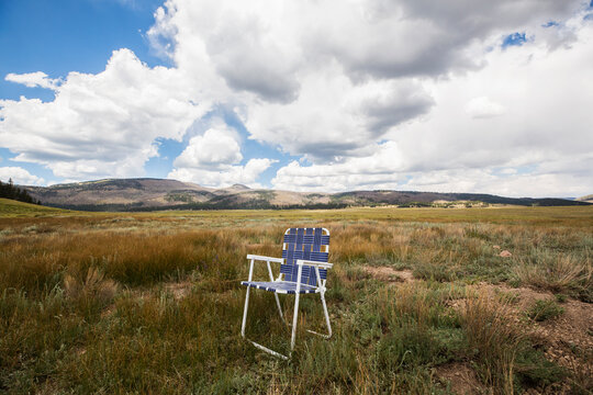 Single folding chair on a plain, mountains in the distance. 