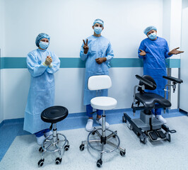 Three office chairs in hospital hall with doctors standing behind. Medics in scrubs showing different emotions.