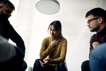 Fototapeta premium Depressed woman sharing her problems with members of group therapy.