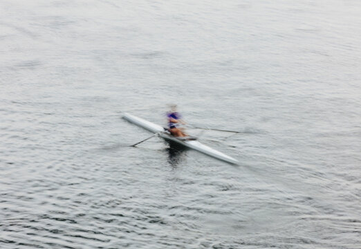 A single scull boat and rower on the water, view from above.