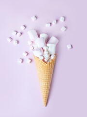 Waffle cone with marshmallows. Pink, white delicate marshmallow on a pink background. Favorite children's sweets. Flat lay.