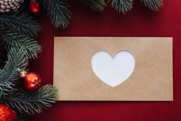 Fir tree branches, Xmas empty envelope on red background. Flat lay, top view, copy space. Concept of letter to Santa Claus