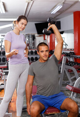 Personal trainer discussing workout plan with young woman at gym