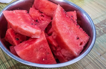 Watermelon slices without a crust in a metal dish close-up on the table background