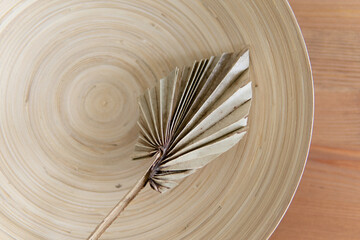 still life greeting card with palm leaf and bamboo plate. grunge wood textured background. style scandinavian
