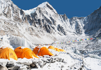 A group of orange tents at a climbers base camp in the Himalayas region. 