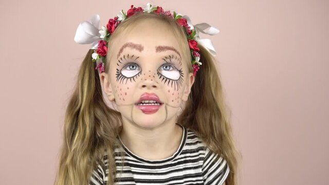 A little girl with make-up on her face depicts puppet grimaces. Carnival costume.Black and white stripes on the shirt. Mime girl.