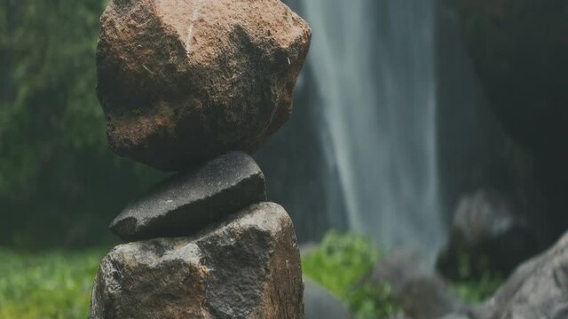 Balanced pebble pyramid tower of stones Obo, tower of your dreams against the background of the waterfall, on anamorphic lens x1.33. Balance, meditation, relaxing, harmony and yoga concept.