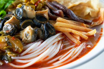 Close-up of a bowl of delicious hot snail meat and three fresh snail rice noodles