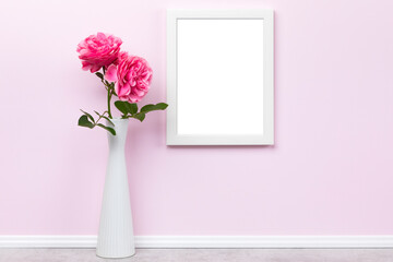 Poster artwork mockup template for online shop with white wooden vertical picture frame on pink wall and vase with roses. Blank image area masked with clipping path.