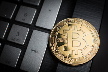 Golden coin with a symbol of Bitcoin cryptocurrency (BTC) on computer keyboard: press the Enter to accept the electronic payment