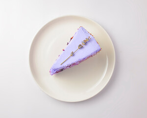 Cut lavander cake on a white plate. A piece of purple violet cake with lavander and berries served on a white plate.