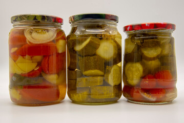 Fototapeta na wymiar Three transparent jars with pickled vegetables on a white background.