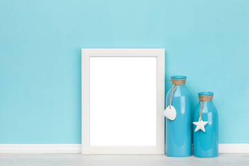 poster artwork online shop mockup template with white wooden vertical picture frame and maritime decoration in front of turquoise wall. Blank image area isolated with clipping path.
