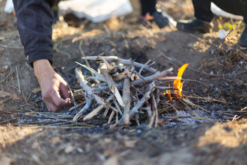 cooking on an open fire. Frying food over a bonfire on a wooden branch - pricking spears in nature. Close-up of a hand. The scouts are preparing lunch.