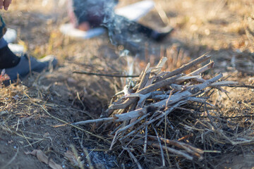 cooking on an open fire. Frying food over a bonfire on a wooden branch - pricking spears in nature. Close-up of a hand. The scouts are preparing lunch.