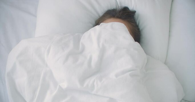 woman Peeking under duvet and smiling. 