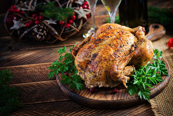 Baked turkey or chicken. The Christmas table is served with a turkey, decorated with bright tinsel. Fried chicken, table setting. Christmas dinner.