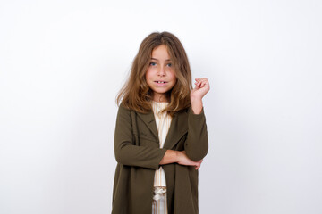 Cheerful Beautiful little girl standing against white background,  with hand near face. Looking with glad expression at the camera after listening to good news. Confidence.