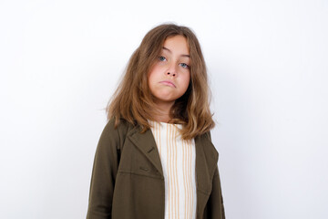 Beautiful little girl standing against white background,  with snobbish expression curving lips and raising eyebrows, looking with doubtful and skeptical expression, suspect and doubt.