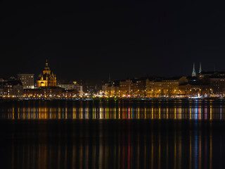 Fototapeta na wymiar Illuminated Helsinki waterfront with Uspenski Cathedral in the background.
