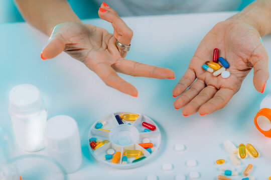 Prescribed medication non-adherence. Female patient counting pills.