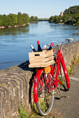 Vieux vélo rouge sur les bords de la Loire en France, bouteille de vin sur le porte bagage.