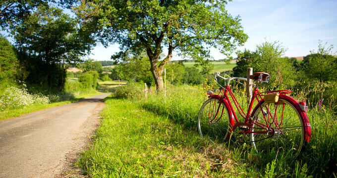 Chemin de campagne au printemps, vieux v&eacute;lo rouge sur le bas c&ocirc;t&eacute;.