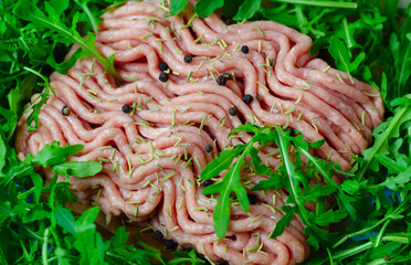 fresh ground turkey meat close up with pepper, rosemary, herbs arugula and spices