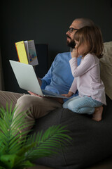 Man trying to work and to read to his daughter at the same time