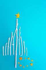 Christmas tree made of white wooden branches on a blue background top view. Festive composition of branches and Christmas decorations flat lay
