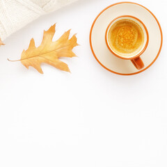 A Cup of coffee, a knitted blanket and autumn leaves on a white wooden background