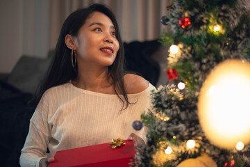 Woman holding christmas gift box for celebrating Christmas at home. young smiling woman celebrating christmas,  Merry Christmas and New Year eve concept.