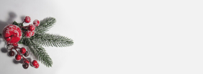 Christmas decorations on a white background. Spruce branch with apple and cherry. Decoration in the snow.