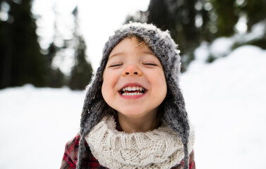 Front view portrait of cheerful small girl standing in winter nature, looking at camera.
