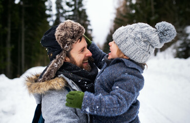 Side view of father with small son in snowy winter nature, talking.