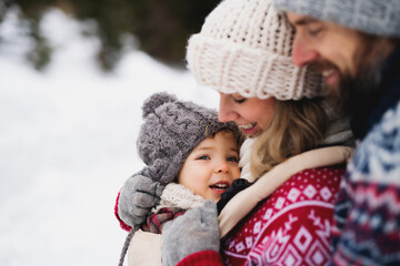 Obraz premium Father and mother with small child in winter nature, standing in the snow.