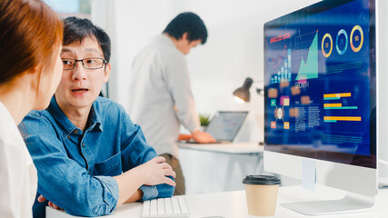 Millennial group of young Asia businessman and businesswoman in small modern urban office. Japanese male boss supervisor teaching intern or new employee korean girl helping with difficult assignment.