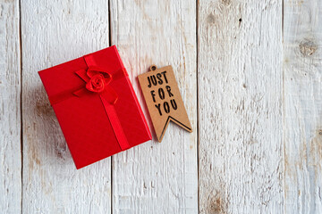 Red box and tag with text just for you on an old wooden background