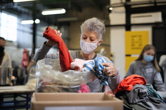 Volunteers working with food and clothes in community charity donations center, coronavirus concept.