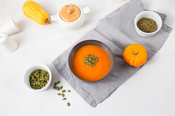 Roasted pumpkin soup with pumpkin seeds on white wooden background. Top view