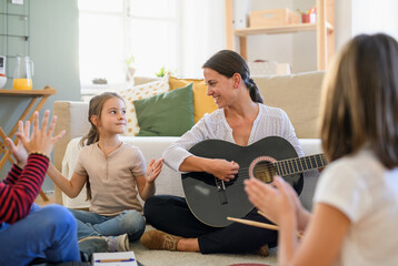 Group of homeschooling children with teacher having music lesson indoors, coronavirus concept.