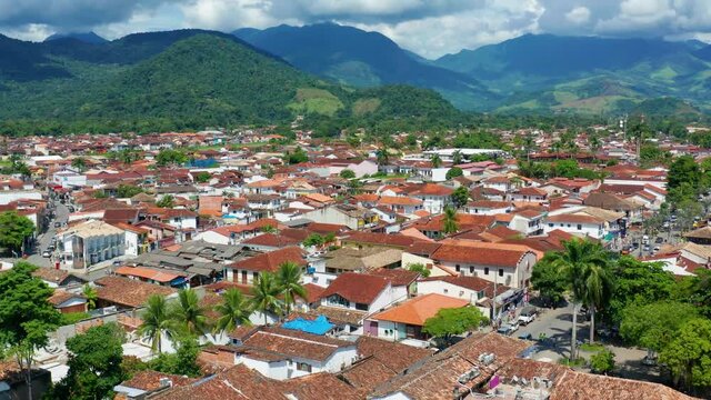 Aerial view over colorful houses in the town of Paraty, towards rainforest and mountains, sunny day, in Brazil - dolly, drone shot