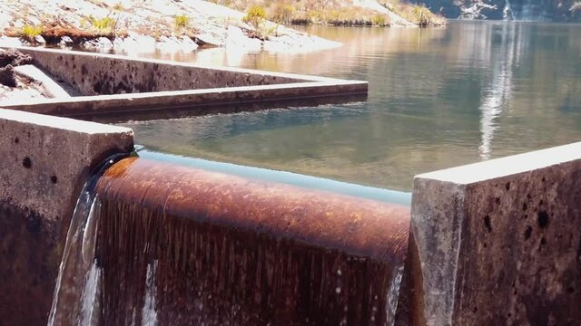 4k daytime and close up on a small waterfall, slowly revealing a beautiful mountain scape with lakes and a hight waterfall. Lakes of Pichgacocha, Ambo, Huanuco, Peru. Tilt up. Wide angle shot